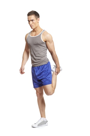 Muscular young man stretching leg in sports outfitの写真素材