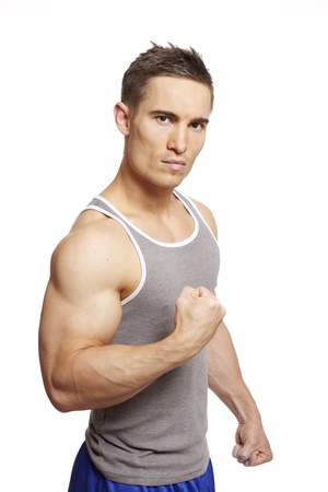 Muscular young man flexing arm muscles in sports outfit on white backgroundの写真素材