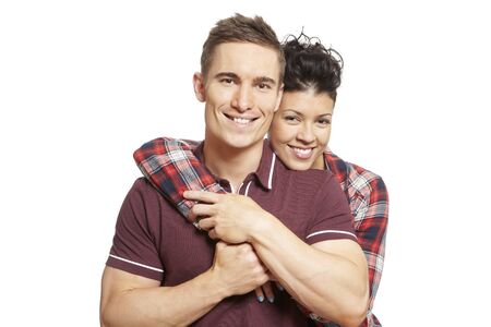 Young couple cuddling and smiling on white background smilingの写真素材