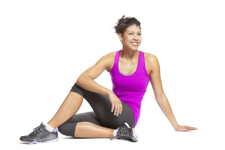 Muscular young woman in yoga pose wearing sports outfit smiling on white backgroundの写真素材