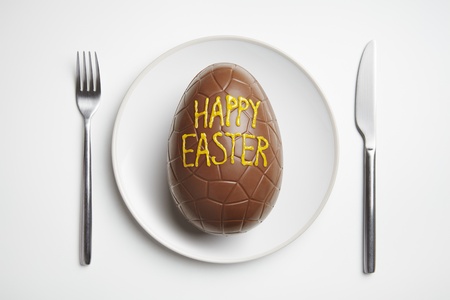 Chocolate easter egg on plate with knife and forkの写真素材