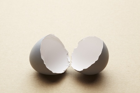 Broken open egg shell on brown tableの写真素材