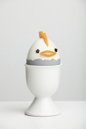 Boiled egg chicken in egg cup on white table topの写真素材