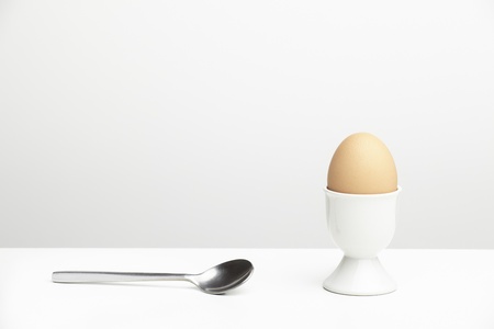 Boiled egg and spoon on white table topの写真素材