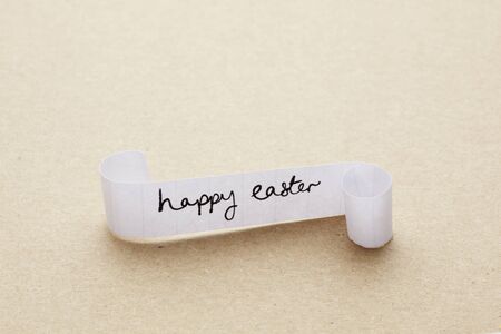 Happy easter message written on paper scroll on brown tableの写真素材