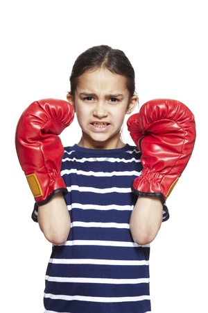 Young girl wearing boxing gloves angry on white backgroundの写真素材