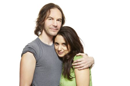 Young mixed race couple cuddling and smiling on white backgroundの写真素材