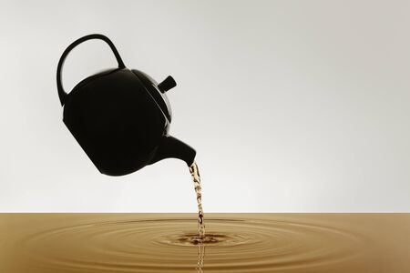 Teapot silhouette pouring tea on grey backgroundの写真素材