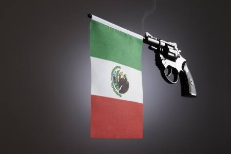 Gun crime concept of hand pistol showing the flag of mexico