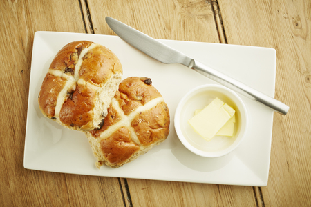 Hot cross bun on white dish and wooden table topの写真素材