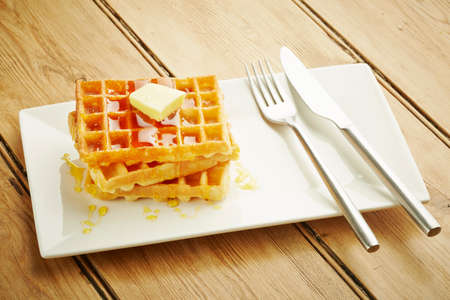 Waffles with syrup on white dish and wooden table topの写真素材
