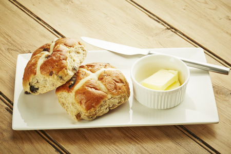 Hot cross bun on white dish and wooden table topの写真素材