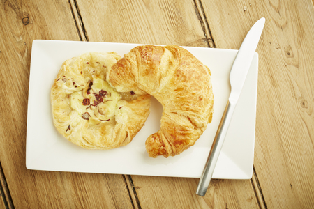 Croissant and custard crown pastries on white dish and wooden table topの写真素材