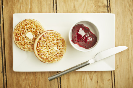 Crumpets toasted on white dish and wooden table top