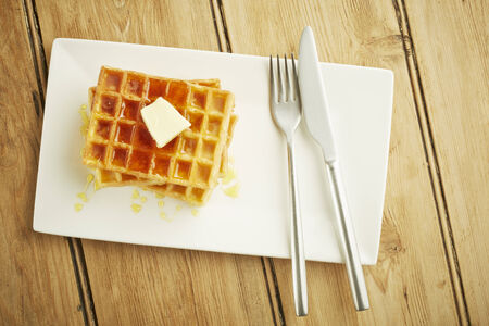 Waffles with syrup on white dish and wooden table topの写真素材