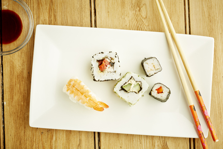 Sushi with chopsticks assorted on white dish and wooden table topの写真素材