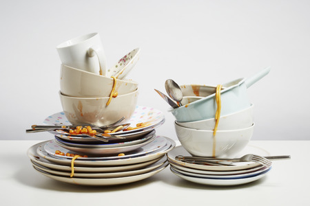 Dirty dishes pile needing washing up. Household chore concept on white backgroundの写真素材
