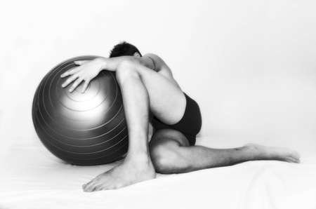   male sitting down on floor behind a big ballの写真素材