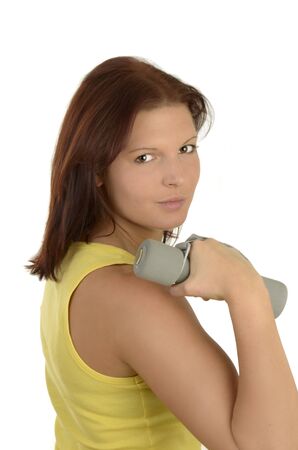 Young woman in a yellow tank top against white background during power training, isolatedの写真素材