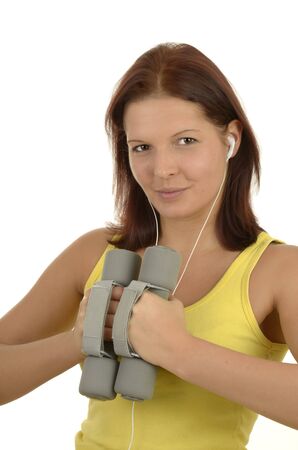 Young woman in a yellow tank top against white background during power training listens to music, isolated, portrait formatの写真素材