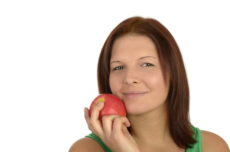 Young pretty woman in green top holding apple to her cheek, smiling,  portrait, Isolatedの写真素材
