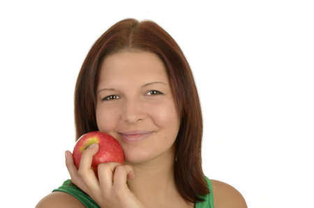 Young pretty woman in green top holding apple to her cheek, smiling,  portrait, Isolatedの写真素材