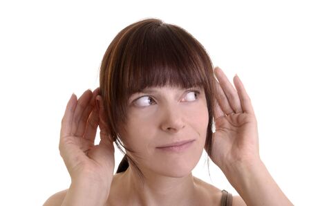 Young woman with auburn hair is listening curiosly, hands holding to her ears, white background, isolatedの写真素材