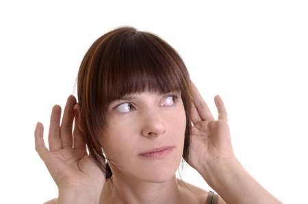 Young woman with auburn hair is listening curiosly, hands holding to her ears, white background, isolatedの写真素材