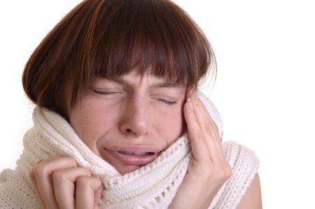 Young woman with a white knitted scarf is sick and has a headache, isolated, close upの写真素材