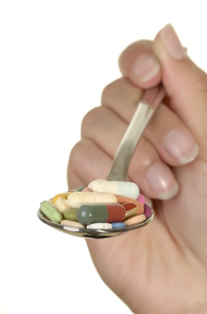 hand holding spoon wih different colorful pills, isolated, white background, copy spaceの写真素材