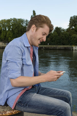 Happy young man text messaging , Outdoor Shotの写真素材