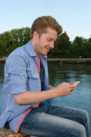 Happy young man text messaging , Outdoor Shotの写真素材