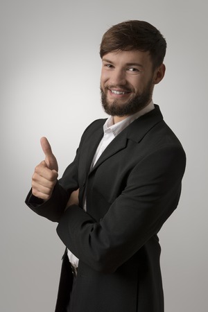 Happy young man with beard thumb up, studio shotの写真素材