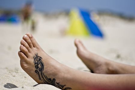 Woman foot with a tattoo in the sandの写真素材