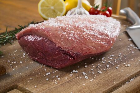 raw steak on wooden board with tomatoの写真素材