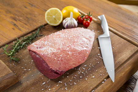 raw steak on wooden board with tomatoの写真素材