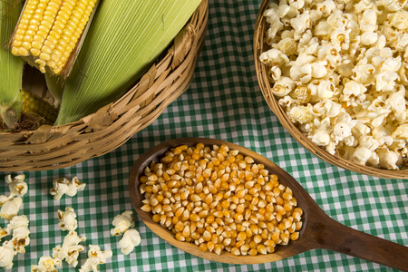 Ear of corn, revealing yellow kernels of maize in a wicker basketの写真素材