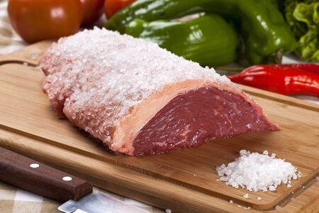 raw steak on wooden board with vegetablesの写真素材