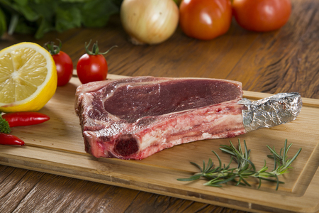 Prime ribs raw on the board with vegetablesの写真素材