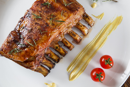 Tasty grilled ribs on board with vegetablesの写真素材