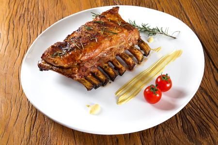 Tasty grilled ribs on board with vegetablesの写真素材
