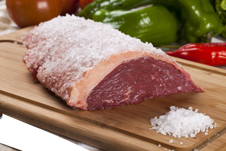 raw steak on wooden board with vegetablesの写真素材