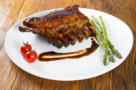 Tasty grilled ribs on board with vegetablesの写真素材