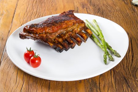 Tasty grilled ribs on board with vegetablesの写真素材