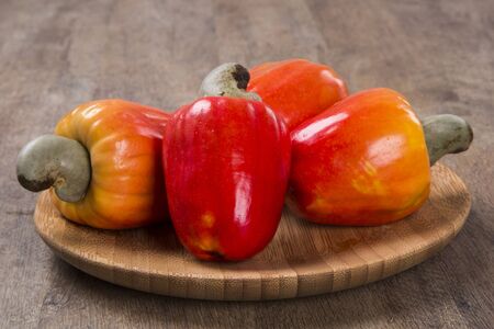 wooden plate with a few cashew over a  wooden surface. Fresh fruit.の写真素材