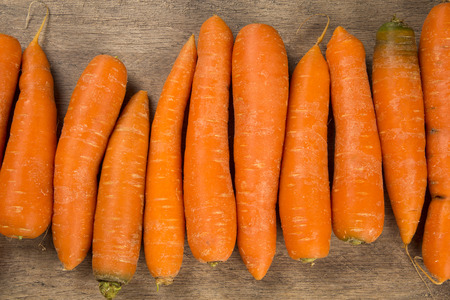 Fresh carrot with green leaves on wooden table. Fresh vegetable.