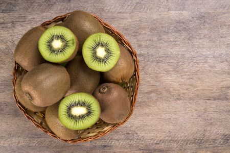 Some kiwis in a basket over a wooden surface. Fresh fruitsの写真素材