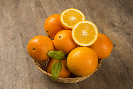 Close up of some oranges in a basket over a wooden surface. Fresh fruit.の写真素材