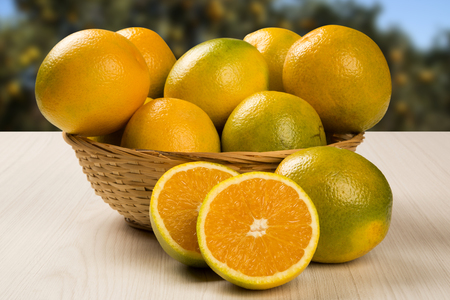 Close up of some oranges in a basket over a wooden surface. Fresh fruit.の写真素材