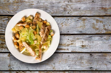Caesar salad with croutons and grilled chicken on wooden tableの写真素材